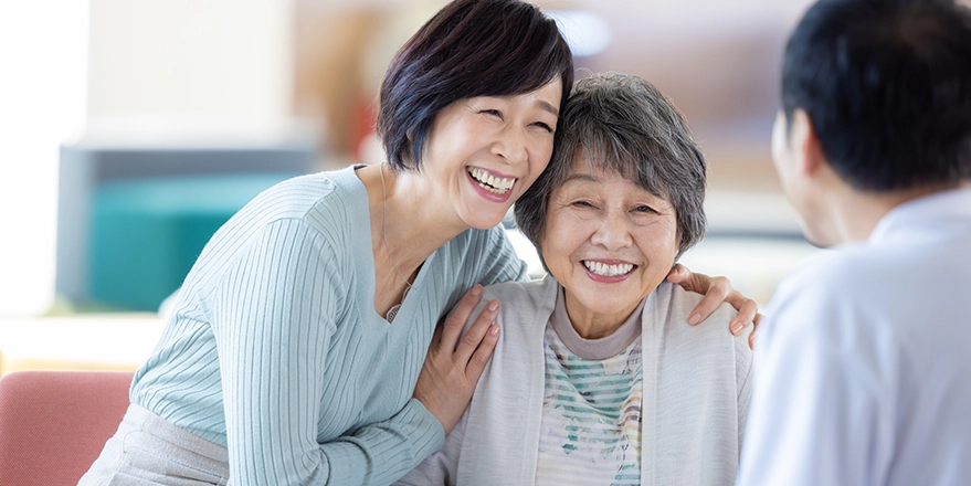 肩を寄せ合って笑顔を見せる女性と高齢女性